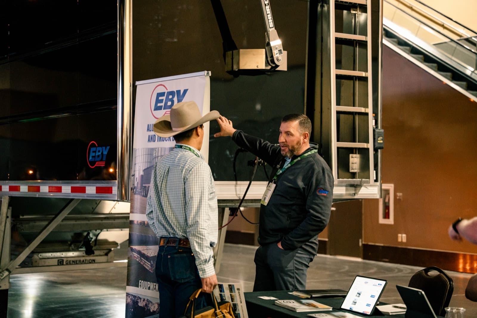An owner-operator talking specs with an exhibitor next to a hopper trailer