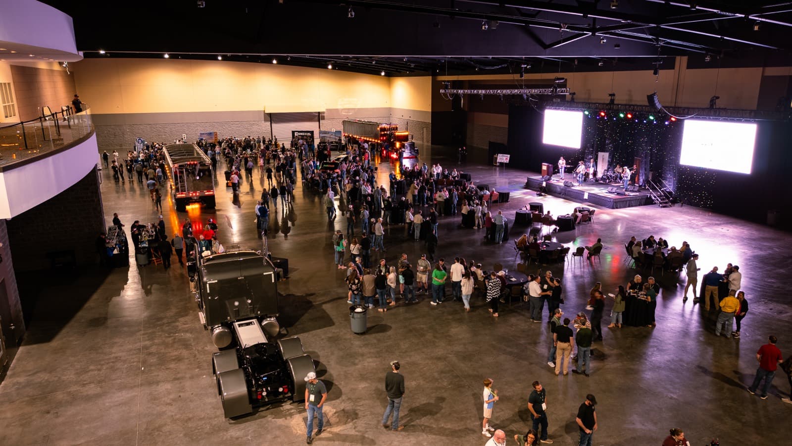 Semi trucks parked on the exhibit hall floor among the crowd